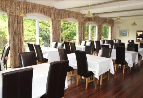 una sala da pranzo con tavoli bianchi e sedie nere di Villa 22 Lanteglos Hotel a Lanteglos