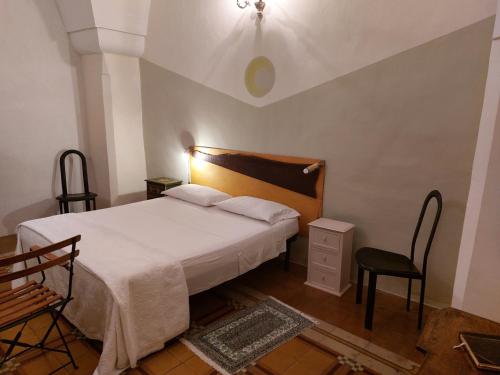 a bedroom with a white bed and a chair at Antica Via delle Aie in Ruffano