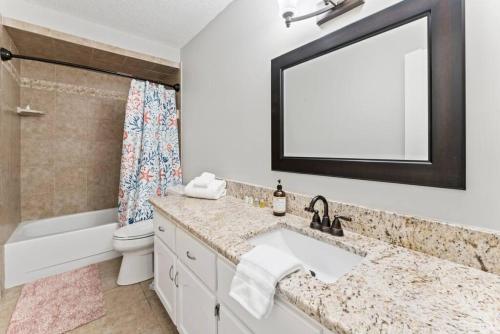 a bathroom with a sink and a toilet and a mirror at Saltwater Oasis - Large Pool in Jacksonville Beach