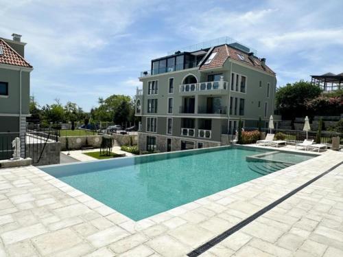 una casa grande con piscina frente a ella en LUXURY APARTMENT in Mediterranea VARNA Complex, sea view and Infinity pool, en Varna