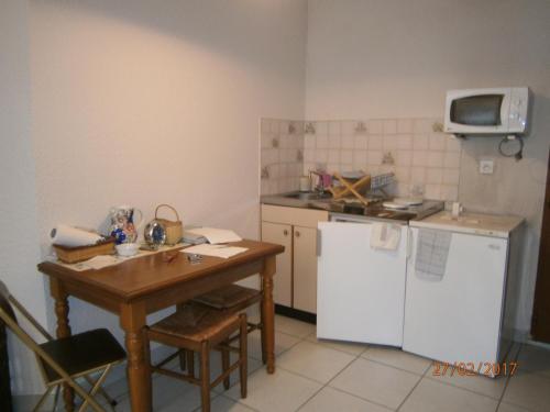 Il comprend une petite cuisine avec une table et un réfrigérateur blanc. dans l'établissement Clos des plages studio avec parking privatif, à La Ciotat
