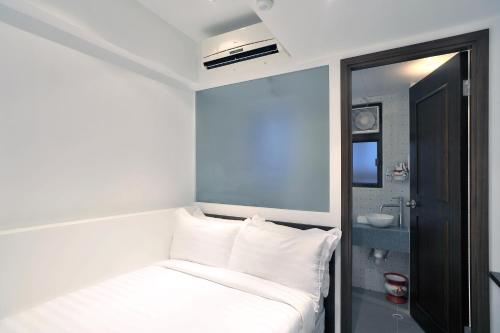 um pequeno quarto com uma cama com almofadas brancas em Mingle by The Park em Hong Kong