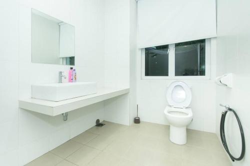 a white bathroom with a toilet and a sink at Beach side spacious 5BR 20pax pool house in Batu Ferringhi