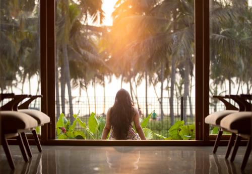 a woman sitting in a window looking out at the water at Bimal's Casa de Papel in Kadikkād