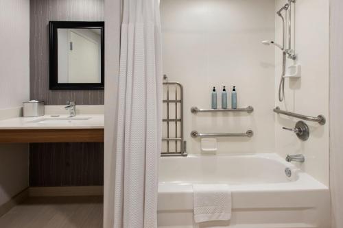 a white bathroom with a tub and a sink at Courtyard Binghamton in Vestal