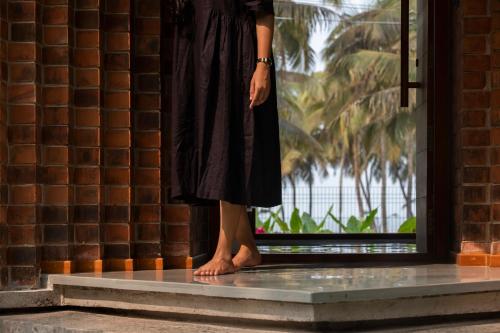 a woman in a black dress standing in front of a window at Bimal's Casa de Papel in Kadikkād