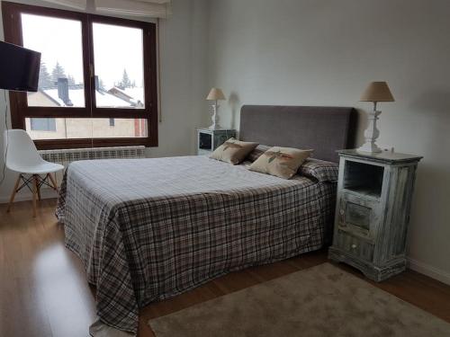 a bedroom with a bed and a television and a window at Vivienda reformada con GARAJE, PISCINA y WIFI in Jaca