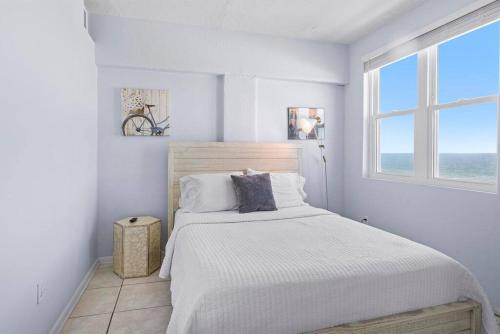 a white bedroom with a bed and a window at Sandpiper Oceanfront 5C in Jacksonville Beach