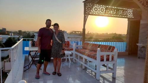 mężczyzna i kobieta stojący na balkonie z zachodem słońca w obiekcie Mama Africa Apts & Studios w mieście Luksor