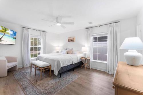 a white bedroom with a bed and two windows at SOBE Retreat - Designers Dream - Fenced backyard in Jacksonville Beach