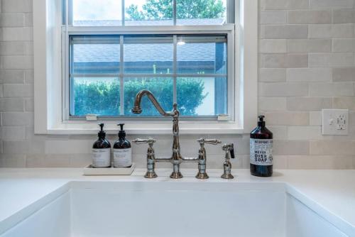 a kitchen sink with a faucet and bottles of wine at SOBE Retreat - Designers Dream - Fenced backyard in Jacksonville Beach