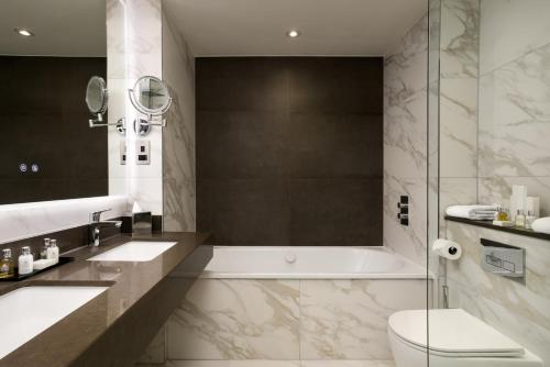 a bathroom with a tub and a toilet and a sink at The Lowry Hotel Manchester in Manchester