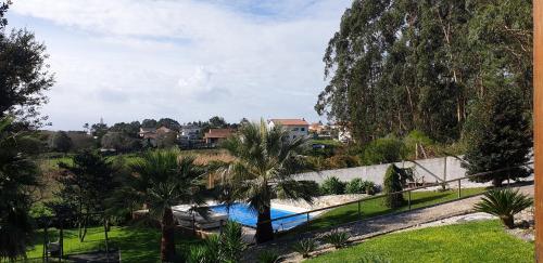 a swimming pool in a yard with palm trees at Quintinha do Periqueiro in Castelo do Neiva