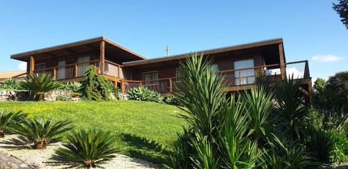 a large wooden house with a lawn in front of it at Quintinha do Periqueiro in Castelo do Neiva