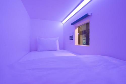 a white room with a bed and a window at Bobopod Alun-Alun, Malang in Malang