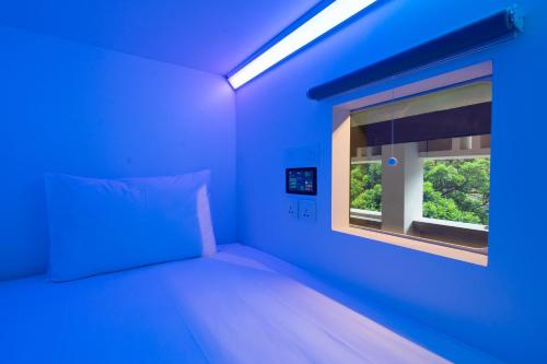 a blue room with a bed and a window at Bobopod Alun-Alun, Malang in Malang
