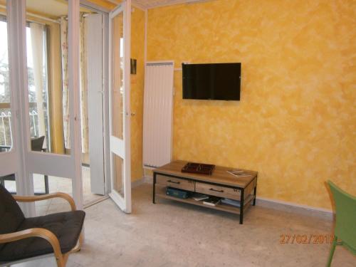 un salon avec une télévision sur un mur jaune dans l'établissement Agréable studio avec cave et parking privatif, à La Ciotat