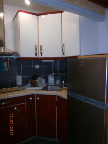 une cuisine avec des armoires blanches et un réfrigérateur noir dans l'établissement Agréable studio avec cave et parking privatif, à La Ciotat