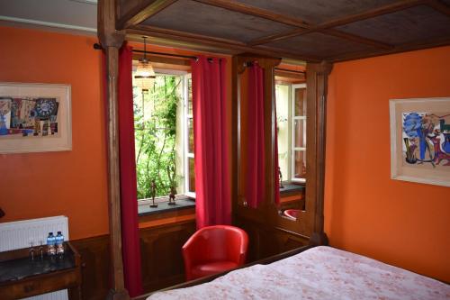 a bedroom with orange walls and a bed and a window at Chateau de Bézyl in Sixt-sur-Aff