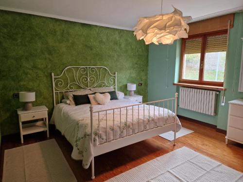 a bedroom with a bed with green walls and a chandelier at Los Kukos Casa Rural in Riaño