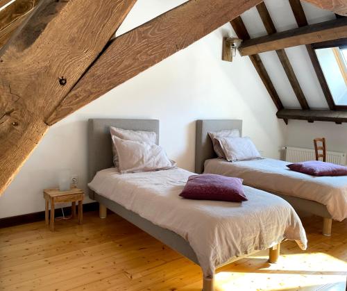 2 Betten in einem Dachzimmer mit Holzdecken in der Unterkunft Chambre d'Aut' in Autun
