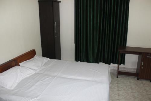 a bedroom with a white bed and a desk at San Unik Homestay in Nilambūr