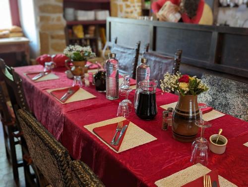 ein Tisch mit einer roten Tischdecke und Silberbesteck in der Unterkunft Chateau De Montmagner in Arnac-la-Poste