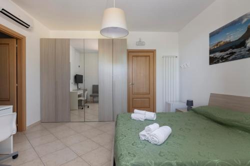 Un dormitorio con una cama verde con toallas. en Villa Vulcano, tra l'Etna e il mare, en Zafferana Etnea