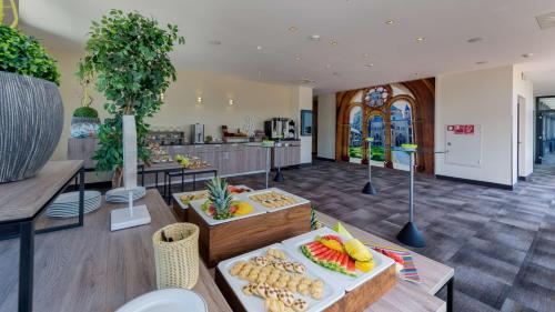 une salle avec des tables et une cuisine dans l'établissement Park Plaza Trier, à Trèves