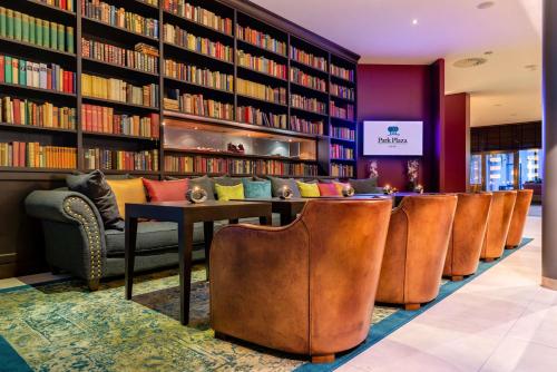 a library with a row of chairs and bookshelves at Park Plaza Trier in Trier