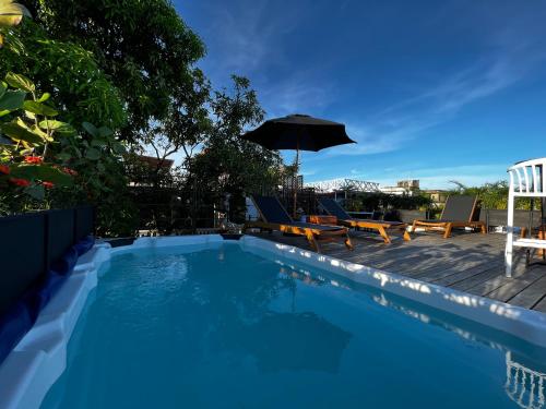 a swimming pool with chairs and an umbrella at Los Patios Hostel in Cartagena de Indias