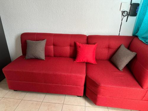 a red couch with three pillows on it at Casa Amueblada en Santa Ana in Santa Ana