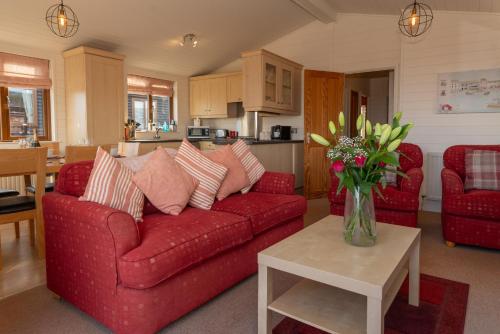 een woonkamer met een rode bank en een vaas met bloemen bij 28 Ocean Terrace Lodge - Mullacott Park in Ilfracombe