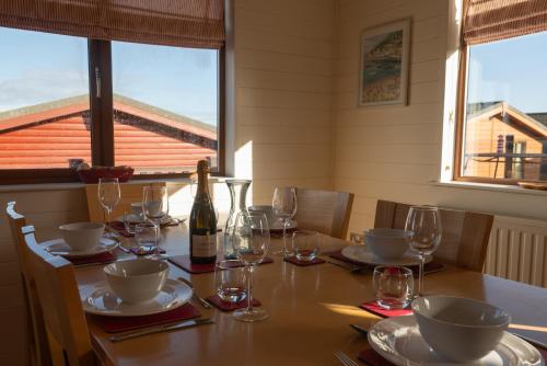 a dining table with glasses and a bottle of wine at 28 Ocean Terrace Lodge - Mullacott Park in Ilfracombe