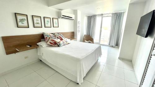 a white bedroom with a bed and a tv at Espectacular Apartamento con Vista al Mar in San Andrés
