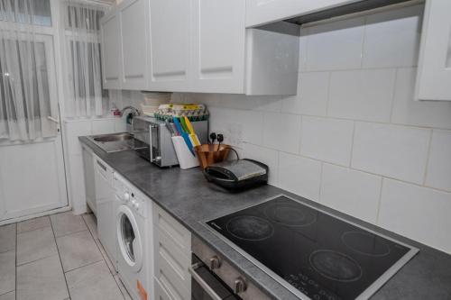 a kitchen with a stove top oven next to a sink at Exclusive single room in Ilford