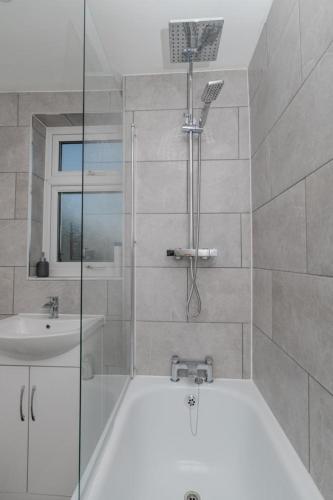 a bathroom with a shower and a tub and a sink at Exclusive single room in Ilford