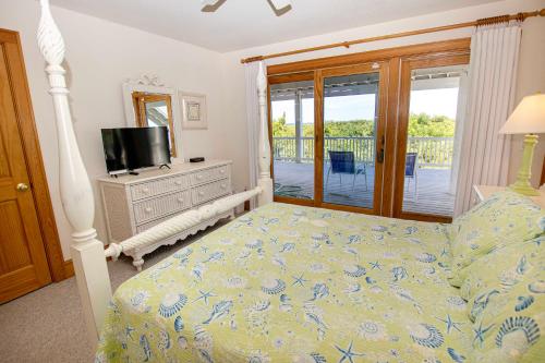 a bedroom with a bed and a television and a balcony at OCEANFRONT, Private Pool, Rec Rm, Ocean Views! PI265, Mroning Star in Sanderling