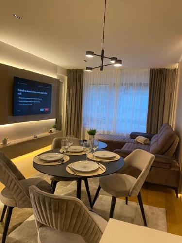 - un salon avec une table, des chaises et un canapé dans l'établissement Miyaki Apartments - BJELASNICA, à Bjelašnica