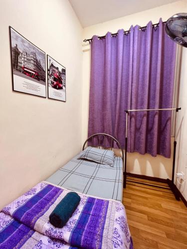 ein kleines Schlafzimmer mit lila Vorhängen und einem Bett in der Unterkunft HOMESTAY MELUR in Sandakan