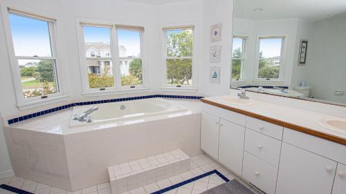 a bathroom with a tub and two sinks and windows at Oceanside, 7 BRs, Private Pool, Den, Rec Rm, 350 ft to Beach access, PI54, Fore Sea Suns in Corolla