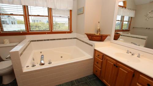 une salle de bain avec une grande baignoire et un lavabo dans l'établissement Oceanside, Private Pool, Volleyball, Screened porch, PI61, Without a Porpoise, à Corolla