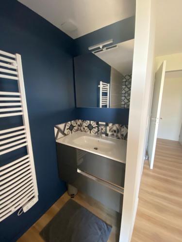 La salle de bains bleue est pourvue d'un lavabo et d'un miroir. dans l'établissement EMERAUDE, à Saint-Cast-le-Guildo
