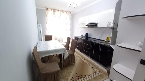 cocina con mesa, sillas y fregadero en 3х комнатная квартира в жилом комплексе ОТАУ сити, en Shymkent