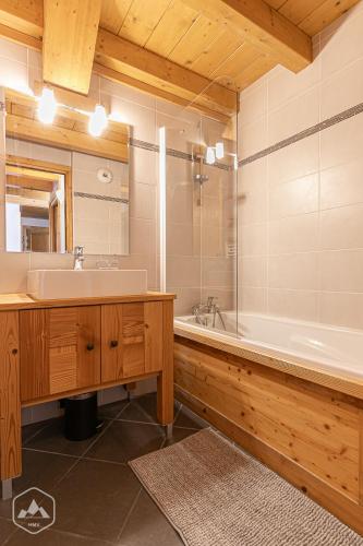 une salle de bain avec un lavabo, une baignoire et un miroir dans l'établissement Le Marteen’s appartement pour 6 personnes à Val Cenis, à Lanslebourg-Mont-Cenis