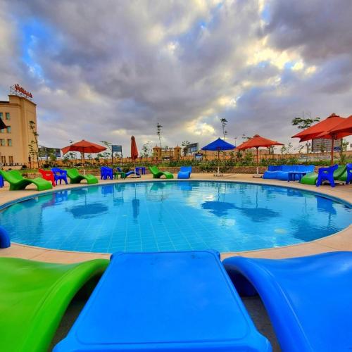 a swimming pool with blue and green chairs and umbrellas at Ramage Hotel & Resort in Cairo