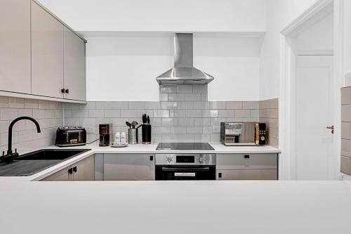 a white kitchen with a stove and a sink at Contemporary Oasis in Paddington II in London