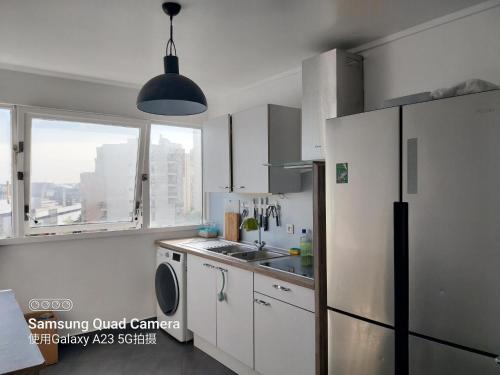 a white kitchen with a refrigerator and a sink at La chambre de l'appartement in Créteil