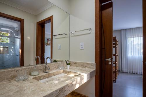 アライアル・ダジュダにあるMuito espaço para criançada brincar! Casa com Piscina e Churrasqueira Privativa! Até 14Paxの洗面台と大きな鏡のあるバスルーム