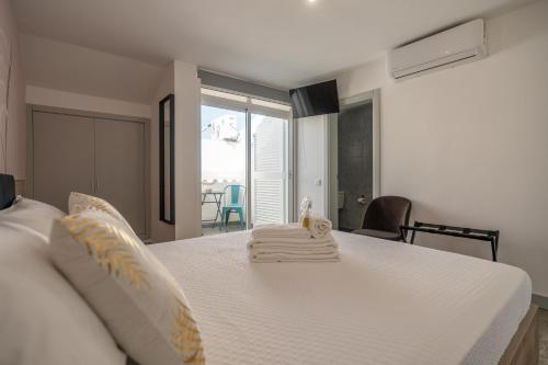 a bedroom with a white bed with towels on it at Leevin Guesthouse in Faro